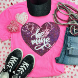 Be Mine SEQUIN HEART Patch, close-up of a sparkling pink sequin heart patch with the words "be mine" written inside, displayed on a pink T-shirt with accessories and shoes for Valentine's Day.