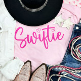 Swiftie Neon Pink Screen Print Heat Transfer, showcasing a pink t-shirt with the word "Swiftie" printed in bright pink neon color.
