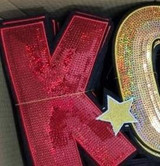 KC Sequin Patch, close-up image of a colorful sequin alphabet patch with shiny red, gold, and star embellishments.
