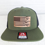 Gun American Flag Leather Hat Patch, green snapback hat with black mesh panels and American flag patch featuring gun silhouettes, decorative leather patch, and brand label Richardson.