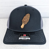 Morel Leather Hat Patch, a detailed patch of a morel mushroom attached to a black and gray trucker cap.