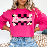 Dramatic DTF Heat Transfer, vibrant pink sweatshirt with a black and pink checkerboard pattern and floral design, featuring the word 'Dramatic' in cursive font.