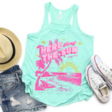 Here Comes The Sun Beach DTF Heat Transfer, a mint green tank top with pink sunset and palm tree graphic and text, accompanied by a straw hat, distressed denim shorts, and white sneakers for summer beachwear.