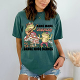Take More Chances Dance More Dances, DTF Heat Transfer graphic T-shirt with cartoon frogs playing guitar and dancing, floral and mushroom accents.