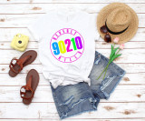 90210 Beverly Hills fan art Sublimation Transfer T-shirt, casual white t-shirt with colorful Beverly Hills 90210 logo, denim shorts, straw hat, sunglasses, tulips, yellow instant camera, brown sandals, summer accessories.