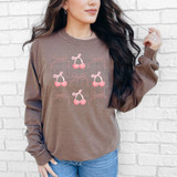 Cherry Bow Collage DTF Heat Transfer, a design of pink cherries with bows on a brown sweatshirt.