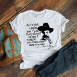 John Wayne Fan Art Don't pick a fight Sublimation Transfer, white T-shirt with a black illustration of John Wayne wearing a cowboy hat and a quote about fighting, positioned on a rustic wooden surface alongside cowboy boots and blue jeans.