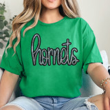 Hornets Sequin Patch, a sparkly black and silver embroidered patch spelling 'hornets' on a green t-shirt worn by a woman.