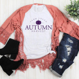 Farm Fresh Autumn Harvest Sublimation Transfer, white t-shirt with purple autumn harvest pumpkin graphic and text, surrounded by a pink lace kimono, distressed jeans, black ankle boots, and a green potted plant on a wooden floor.