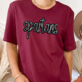 Spartan Sequin Patch, eye-catching black and silver sequin embroidered patch on a maroon T-shirt.