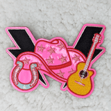 Country Western Collage PINK Embroidered Vinyl HAT/POCKET Patch, a colorful patch featuring a pink cowboy hat with star patterns, a yellow guitar, and a pink horseshoe with a black background, suitable for clothing or accessories.