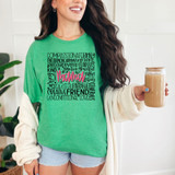 Mama Word Collage DTF Heat Transfer, colorful design on a green T-shirt with positive words such as 'kind', 'brave', 'love', and 'daughter' in various fonts, worn by a smiling woman holding a cup of coffee.