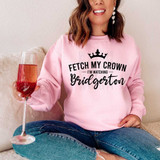 Fetch My Crown I'm Watching Bridgerton BLACK DTF Heat Transfer, product image of a woman wearing a pink sweatshirt with the text and crown design, holding a glass of rose wine.