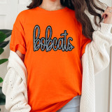 Bobcats Sequin Patch, close-up of a woman wearing an orange T-shirt with a large black and silver sequin applique of the word 'bobcats' on the front.