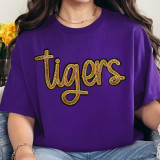 Tigers Gold Sequin Patch, a glittery gold and black embroidered patch in the shape of the word 'Tigers' with sequins embellishing the text, sewn onto a vibrant purple T-shirt.