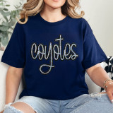 Coyotes Sequin Patch, close-up of a navy blue t-shirt featuring a sparkly sequin patch with the word 'coyotes' and a cross design, worn by a woman with blonde curly hair.