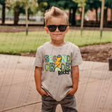 Second Grade Rocks Blue/Green DTF Heat Transfer, colorful graphic tee shirt with rocks and lightning bolt design worn by a young boy at the park.