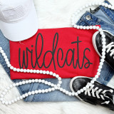 Wildcats Black PUFF Screen Print Heat Transfer, a black puff screen print design with a three-dimensional raised texture, displayed on a red fabric surface, surrounded by casual clothing and accessories.