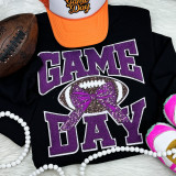 Purple Chenille Football Game Day with Sequin Bow Patch, close-up of a black sweatshirt with purple and white lettering, a football, an orange cap, pink and white sneakers, and pearl accessories.