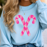 Pink Sequins Candy Canes Patch, a sparkly pink sequin patch in the shape of candy canes crossed in an 'X' design on a light blue sweatshirt.