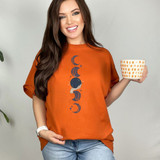 Moons DTF Heat Transfer, a woman wearing an orange T-shirt with moon phase designs and holding a polka dot mug.