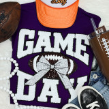 White Chenille Football Game Day with Sequin Bow Patch, close-up of a purple T-shirt with a sequined football hat and bow patch, orange cap, brown football, black sneakers, and accessories.
