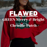FLAWED GREEN Merry & Bright Chenille Patch, close-up view of the holiday-themed patch on a red sweater worn by a smiling woman outdoors in a snowy landscape, with snow-covered trees in the background.