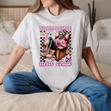 True Crime And Chill Skeleton DTF Heat Transfer, graphic of a skeleton with gray hair in a pink hoodie sitting in an armchair with a drink, surrounded by flowers and checkered background.
