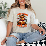 Give Thanks To the Lord Faux Sequins DTF Heat Transfer, a woman wearing a beige t-shirt with a colorful sequin pumpkin design and the text 'Give Thanks To the Lord' inspired by Psalm 136:1.