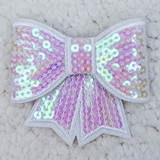 White Iridescent Sequin Bow Hat/Pocket Patch, decorative white bow with pink and iridescent sequins and embroidery, suitable for accessories or clothing embellishments.
