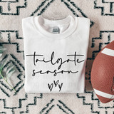 Tailgate Season BLACK DTF Heat Transfer, printed on a white t-shirt with handwritten-style text and hearts, displayed with a football on a patterned rug.
