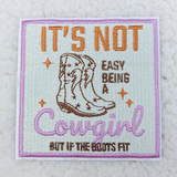 It's Not Easy Being A Cowgirl Embroidered HAT/POCKET Patch, embroidered patch featuring cowboy boots, floral details, and colorful text with pink border on a white background.
