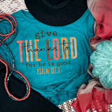Give Thanks To The Lord For He Is Good Psalm 107:1 DTF Heat Transfer, colorful and inspiring religious t-shirt design on a blue shirt, displayed with decorative beads, a hat, and fabric accessories.