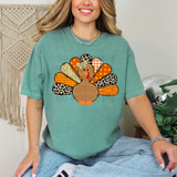 Patterned Turkey DTF Heat Transfer, colorful turkey design with patterned feathers in animal print, glitter, and plaid on a woman's T-shirt.