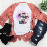 Time to recharge Crystal Sublimation Transfer, colorful crystal designs on a white t-shirt with a pink lace cardigan, distressed jeans, and black boots laid out on a white wooden surface.