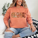 Nurse Fall Pattern DTF Heat Transfer, colorful floral and pumpkin pattern inside the word 'NURSE' on a peach sweatshirt.
