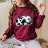 Black and White Pumpkins DTF Heat Transfer, Halloween themed pumpkins with black and white spotted designs on a burgundy sweatshirt worn by a woman.