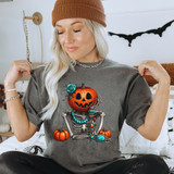 Turquoise Pumpkin Skeleton DTF Heat Transfer, woman wearing a Halloween themed t-shirt with a turquoise and orange skeleton pumpkin design.