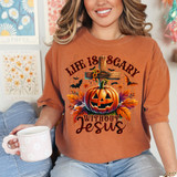 Life Is Scary Without Jesus DTF Heat Transfer, a woman wearing an orange t-shirt with a Halloween pumpkin and cross design, surrounded by autumn leaves and bats.