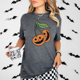 Pumpkin Cherries *Glitch Effect* DTF Heat Transfer, Halloween-themed design on a gray T-shirt worn by a woman, featuring vibrant orange and black pumpkins with a glitch effect, surrounded by Halloween bat decorations.