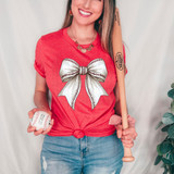 Baseball Coquette Bow DTF Heat Transfer, image of a woman wearing a red t-shirt with a large metallic bow design on it, holding a baseball and a wooden bat.