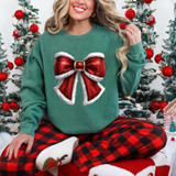 Vintage Red Bow DTF Heat Transfer, Christmas-themed red bow with white trim and metallic buckle design on a woman wearing a festive green sweatshirt with Christmas trees in the background.