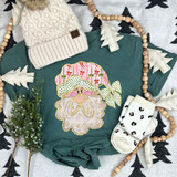 Coquette Bow Santa Faux Glitter DTF Heat Transfer, christmas-themed image of a sweatshirt with a Santa face design, surrounded by holiday decor like a knit hat, wooden bead garland, and white gloves.