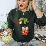 Faux Glitter Green Hand DTF Heat Transfer, image of a woman wearing a black sweatshirt with a decorative Christmas ornament and bow design made from green, red, white, and black glittery faux glitter materials.