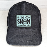 Let It Snow Somewhere Else FAUX Leather Patch, black baseball cap with a decorative patch featuring snowflakes and the phrase "Let it Snow somewhere else" in black text.