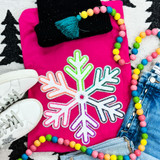 Multi-Colored Chenille/Sequin Snowflake Patch, vibrant snowflake patch with multi-colored edges on a pink background surrounded by white sneakers, a black beanie with a blue tassel, a colorful bead necklace, and denim jeans.