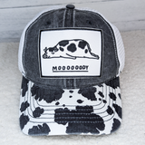 Moooooody Embroidered Hat with Quote and Cow Pattern Pocket Patch, black and white trucker cap with cow print brim and embroidered patch featuring a lying cow and the word MOOOOODY.