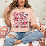 Howdy Valentine Western DTF Heat Transfer, a pink t-shirt with a Valentine's Day themed graphic design featuring hearts, cowboy boots, hats, and phrases like 'cowboys', 'xoxo', 'howdy', and 'y'all'.