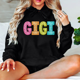 Bright Groovy Gigi Faux Sequins DTF Heat Transfer, a woman wearing a black hoodie with multicolored sequined GIGI letters on the front.