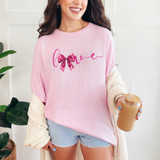 Cursive Love Bow DTF Heat Transfer, pink cursive text with a pink bow graphic on a woman's pink T-shirt.